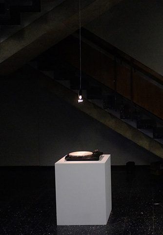 Plattenspieler auf weißem Sockel in einem dunklen Treppenhaus